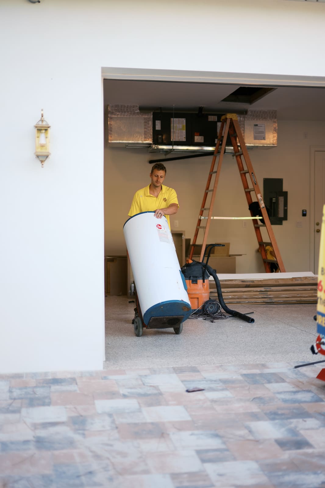 Josh carrying a new water heater through a garage